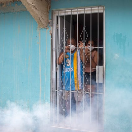 Santo Domingo residents watch from their homes as disinfectant is sprayed in the street as a preventive measure against the coronavirus in April. Photo: AFP