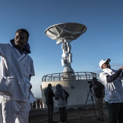 People take selfies in front of a satellite antenna in Ethiopia. Photo: AFP