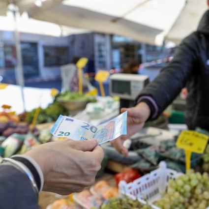 A customer hands a 20 Euro banknote to a vendor at a stall selling fruit and vegetables in Rome, Italy, earlier this month. Photo: Bloomberg