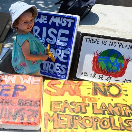 A child stands next to placards before a climate strike rally in Central on September 20, 2019. Despite several firms making high-profile pledges to improve their sustainability and business practices, the effectiveness of relying on companies’ enlightened self-interest remains unclear. Photo: AFP