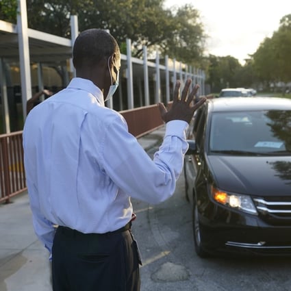 A US school employee waves to parents as they drop off their children at school. Photo: AP Photo