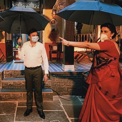 Actors rehearse a scene for Indian television series Bhakharwadi – holding umbrellas to make sure they are standing far enough apart for social distancing. Photo: DPA