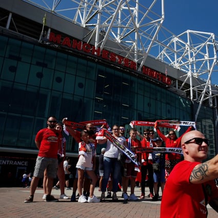 Manchester United fans pose for a photo outside the club’s Old Trafford stadium. Photo: Reuters