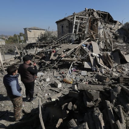 Men look at the ruins of a house following shelling in the breakaway region of Nagorno-Karabakh. Photo: Reuters
