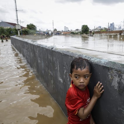 An Indonesian boy stands next to a wall at a flooded road in Jakarta, Indonesia, on January 2. Up to 95 per change of north Jakarta could be submerged by 2050 due to climate change, and climate-change-related insurance products are available in Indonesia. Photo: EPA-EFE