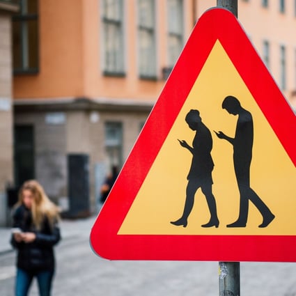 A road sign warning against pedestrians focusing on their smartphones is seen near the old town in Stockholm. Sweden is the latest European country to ban use of telecoms gear from Huawei Technologies and ZTE Corp for upcoming 5G mobile networks. Photo: Agence France-Presse