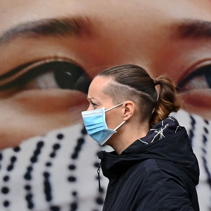 A pedestrian walks past a poster of a person wearing a face covering in West London on October 11. Over the past few months, Europe’s largest economies have been hit by a second wave of infections that is forcing governments to reimpose restrictions. Photo: AFP