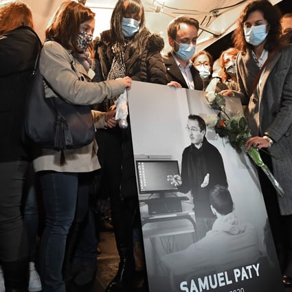 Relatives and colleagues hold a picture of Samuel Paty during a national homage to the late French teacher in Conflans-Sainte-Honorine, northwest of Paris, on Tuesday. Photo: AFP