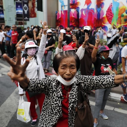 Pro-democracy protesters flashing three-fingered salutes near a main shopping district in Bangkok on Sunday. Photo: AP