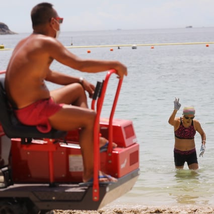 A swimmer comes out of the water as a lifeguard looks on at a beach in Clear Water Bay on July 25. Hong Kong has closed beaches as part of its coronavirus containment measures. Photo: Dickson Lee