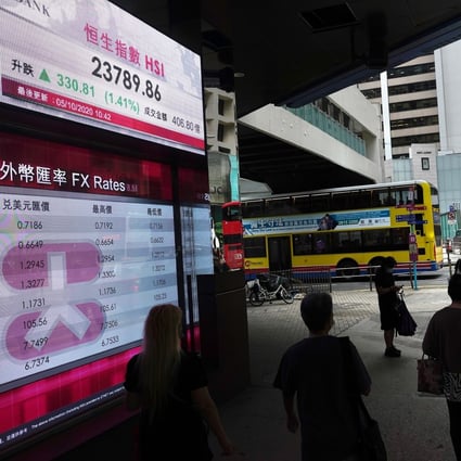 People walking past a bank's electronic board showing stock index and prices near the Exchange Square in Central, Hong Kong. Photo: AP