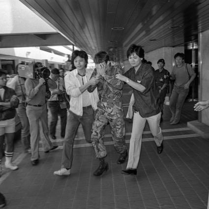 One of the two soldiers is escorted from Kai Tak airport after surrendering to police. Photo: SCMP