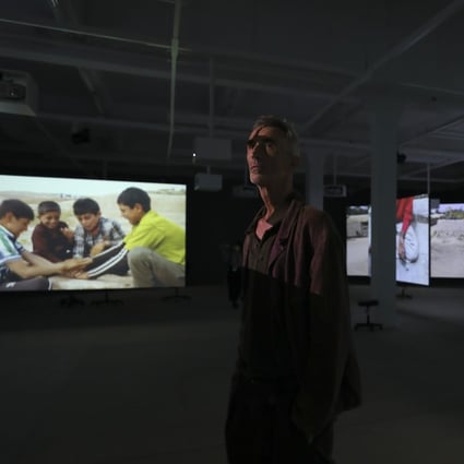 Francis Alÿs poses amid his installation “Children‘s Games”, a series of videos of children at sites of conflict playing, part of his exhibition at Tai Kwun Contemporary in Central, Hong Kong. Alÿs is a Belgian-born, Mexico-based artist. Photo: Xiaomei Chen