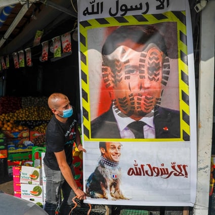 A Palestinian in East Jerusalam erects a mural with the slogan “Anyone but the Prophet” and the portrait of French President Emmanuel Macron with boot prints and placed on the body of a dog. Photo: AFP