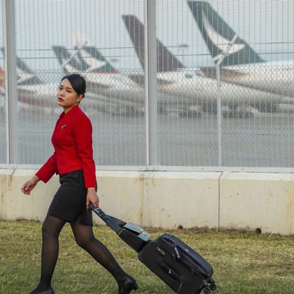 A Cathay Pacific staff member walks by an aircraft bay with some of the carrier’s parked planes. Photo: Robert Ng