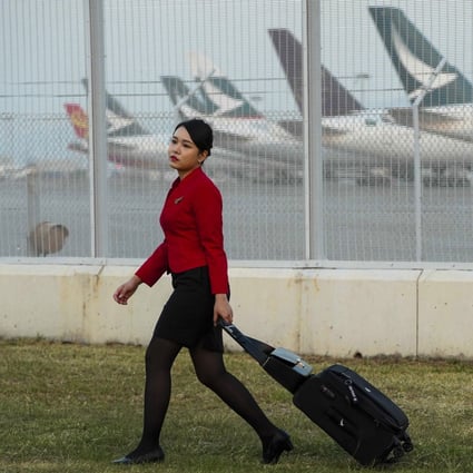 A Cathay Pacific flight attendant wheels her luggage past a parking bay for the company’s aircraft on October 26. Photo: Robert Ng