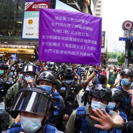 A police officer raises a purple banner warning protesters in Causeway Bay on October 1 that they might be violating the national security law, which took effect just before midnight on July 1. Photo: Sam Tsang