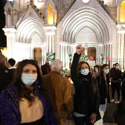 A woman raises her fist outside Notre-Dame de l'Assomption Basilica in Nice on Saturday, to pay tribute to the three victims of a knife attacker. Photo: AFP