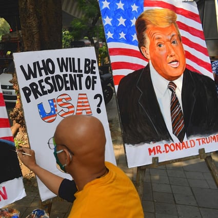 An artist paints an image of Joe Biden next to a painting of US President Donald Trump in Mumbai, India. Photo: AFP
