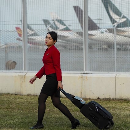A Cathay Pacific flight attendant wheels her luggage past a parking bay for the company’s aircraft. Photo: Robert Ng