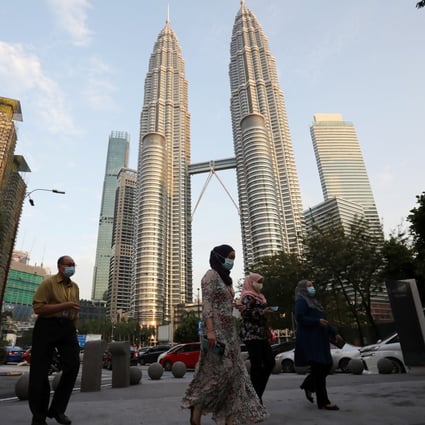 People wearing masks cross a street in front of Petronas Twin Towers in Kuala Lumpur, Malaysia. Photo: Reuters