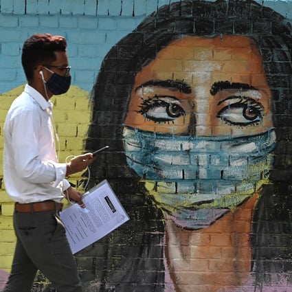 A man walks past a mural in New Delhi depicting a woman wearing a mask on Saturday. Photo: AFP