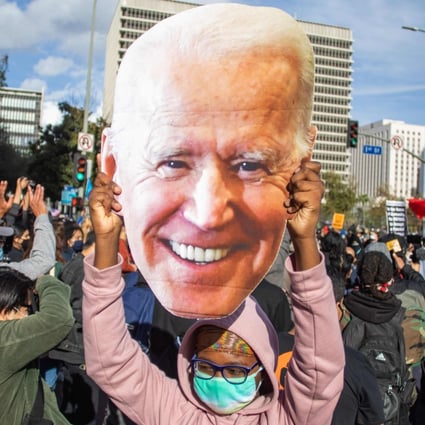 A supporter holds a large cut-out of Joe Biden’s face as people march in Los Angeles to celebrate his election victory on Saturday. Photo: AFP