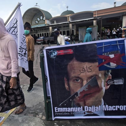 Muslim men walk past a defaced poster of French President Emmanuel Macron during a protest in Medan, North Sumatra, Indonesia on Friday. Photo: AP Photo