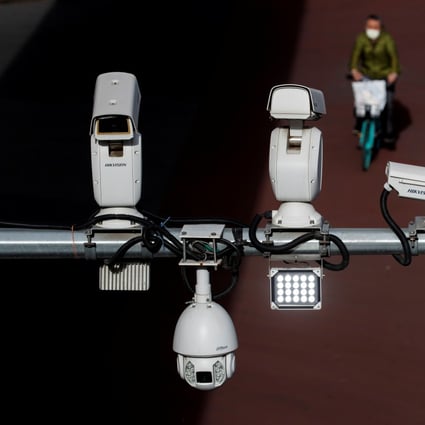 Security surveillance cameras overlook a street as a man cycles past in Beijing, May 11, 2020. Photo: Reuters