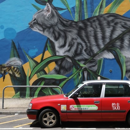Street art forms the backdrop for a passing taxi in Wan Chai on August 20. A bill proposing to introduce a premium franchised taxi service in Hong Kong has been dropped in view of the operating difficulties faced by the trade amid the economic downturn. Photo: Nora Tam