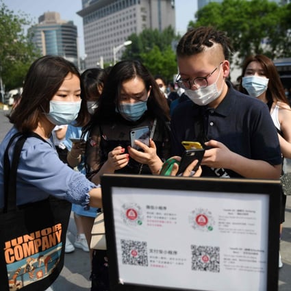 Shoppers use a phone app to scan a code to confirm their health and travel status before being allowed to enter a mall in Beijing in May. Photo: AFP
