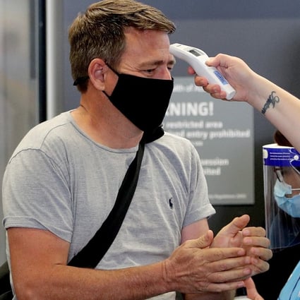 A passenger arriving in Perth from Brisbane has his temperature checked. Australia’s hard border restrictions were eased, as a new coronavirus cluster emerged in South Australia. Photo: EPA-EFE