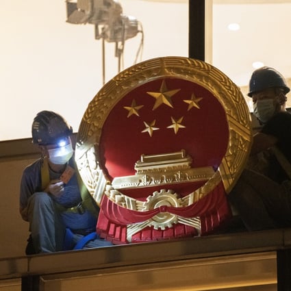 Workers place a national emblem outside the Metropark Hotel in Causeway, as the four-star property became the new temporary headquarters of the Office for Safeguarding National Security, on July 8. Photo: Robert Ng