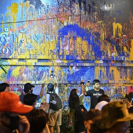 Pro-democracy protesters pose for photos next to the paint-splattered sign for the police headquarters during an anti-government rally in Bangkok. Photo: AFP