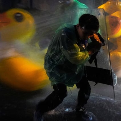 A demonstrator uses a shield as a protection against water cannons, with inflatable rubber ducks in the background, during a pro-democracy protest in Bangkok. Photo: Reuters