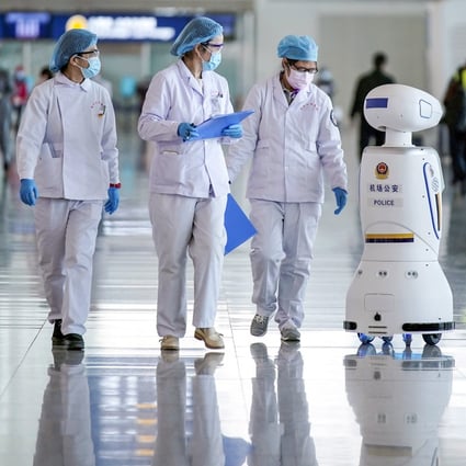Medical workers walk by a police robot at the Wuhan Tianhe International Airport after travel restrictions on leaving Wuhan were lifted on April 8. Photo: Reuters