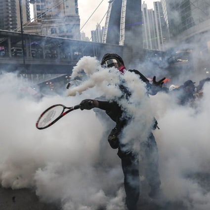 An anti-government protester uses a tennis racquet to return a tear gas canister fired by police in Tsuen Wan on August 25, 2019. Photo: Sam Tsang