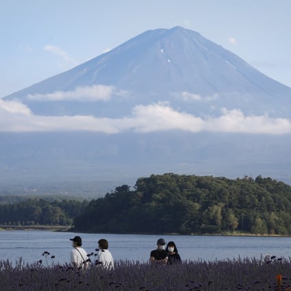 Visitors admire blooming fields of wild lavender next to Lake Kawaguchi against the backdrop of Mount Fuji at Oishi Park in Yamanashi, Japan, on July 19. The Japanese government’s ‘Go To Travel’ domestic tourism campaign is among its many efforts to sustain the country’s economy amid a drop in foreign visitors. Photo: EPA-EFE