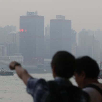 Tourists in Tsim Sha Tsui look across Victoria Harbour on a poor air quality day in November 2018. Photo: Sam Tsang