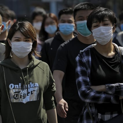 People wearing protective face masks to prevent the spread of the new coronavirus walk across a street in Beijing on Sunday, April 12, 2020. Photo: Andy Wong