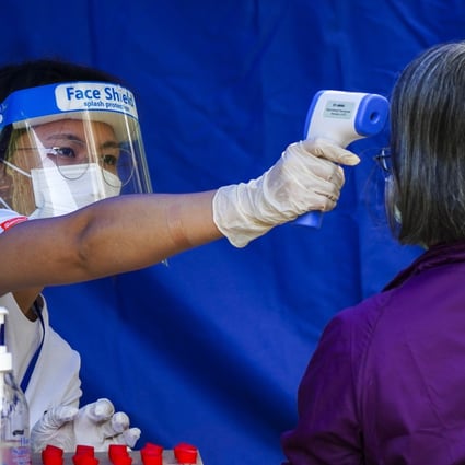 A medical worker takes a woman’s temperature at temporary testing centre for Covid-19 at Fu Shin Community Hall in Tai Po on November 9. How to identify and train workers to handle and administer vaccines and determining the location for administering shots are decisions Hong Kong’s government will have to make soon. Photo: Sam Tsang