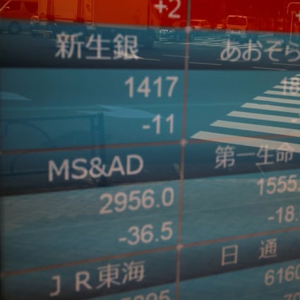 Passers-by wearing protective face masks are reflected on a stock quotation board outside a brokerage in Tokyo on September 17, 2020. Photo: Reuters