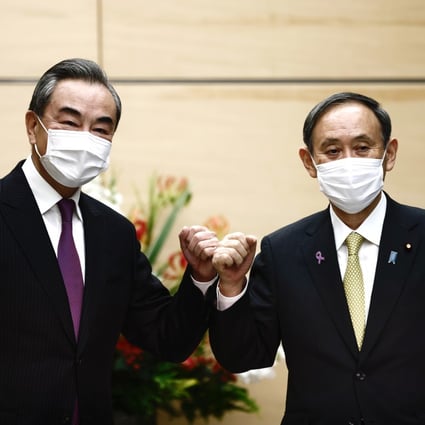 Chinese Foreign Minister Wang Yi (left) bumps elbows with Japanese Prime Minister Yoshihide Suga ahead of their meeting in Tokyo on Wednesday. Photo: Bloomberg