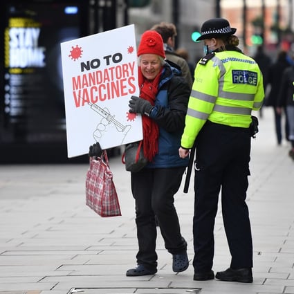 Police officers speak to a protester at an anti-vaccine demonstration outside the offices of the Bill and Melinda Gates foundation in central London on November 24. Photo: AFP