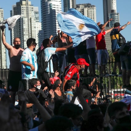 People climb on the fence of the Casa Rosada presidential palace as they gather to mourn the death of soccer legend Diego Maradona in Buenos Aires on Thursday. Photo: Reuters