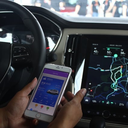 A driver demonstrates how to connect SAIC's Roewe RX5 sports-utility vehicle with his mobile phone using Alibaba's YunOS operating system on 6 July 2016. Photo: SCMP
