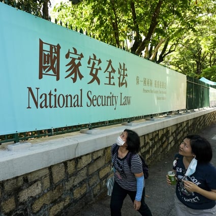 Two women look up at a banner advertising the national security law on Albany Road in Central on June 30. The law, unanimously passed in Beijing, took effect in Hong Kong at 11pm that day. Photo: Felix Wong