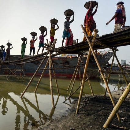 Labourers unload coal from a cargo ship in Gabtoli on the outskirts of Dhaka, Bangladesh, on November 6, 2019. Developing countries such as Bangladesh are reducing their dependence on coal, raising the importance of environmental considerations in infrastructure investment. Photo: AFP