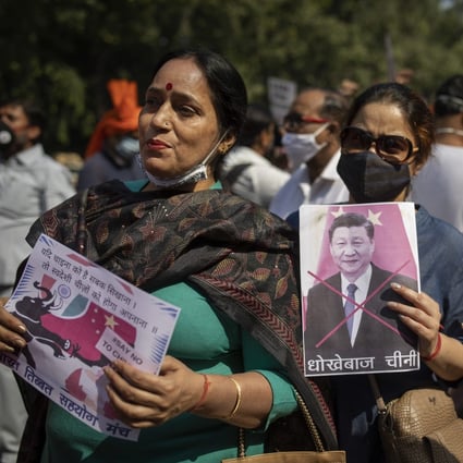 A woman holds a vandalised photograph of Chinese President Xi Jinping at a protest near the Chinese embassy in New Delhi, India. Photo: AP