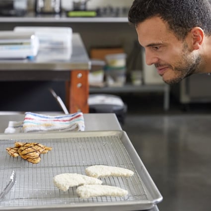 An employee of Eat Just inspects grilled fillet made from lab-grown cultured chicken. Photo: via Reuters